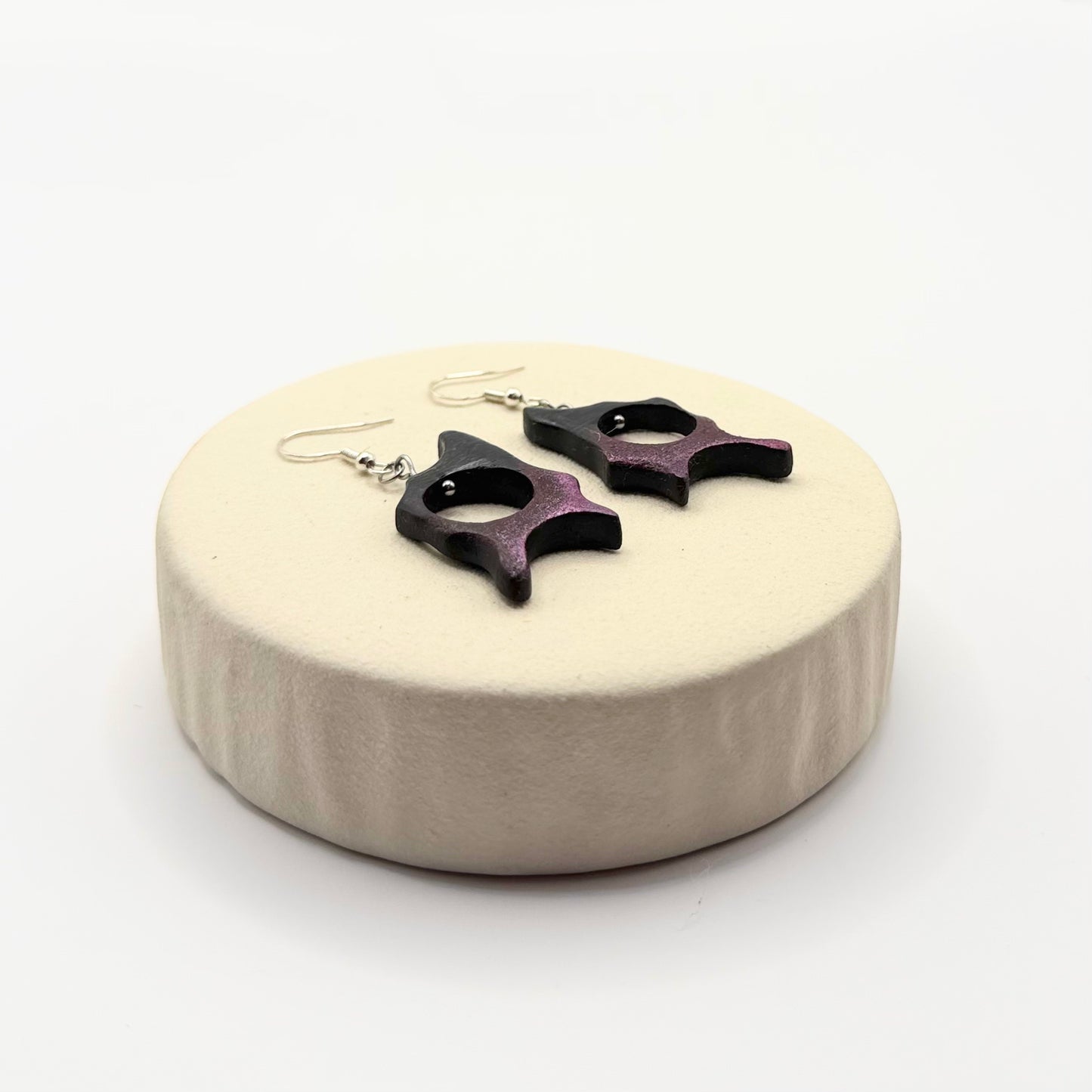 Artistic purple and black bog oak earrings displayed from the side