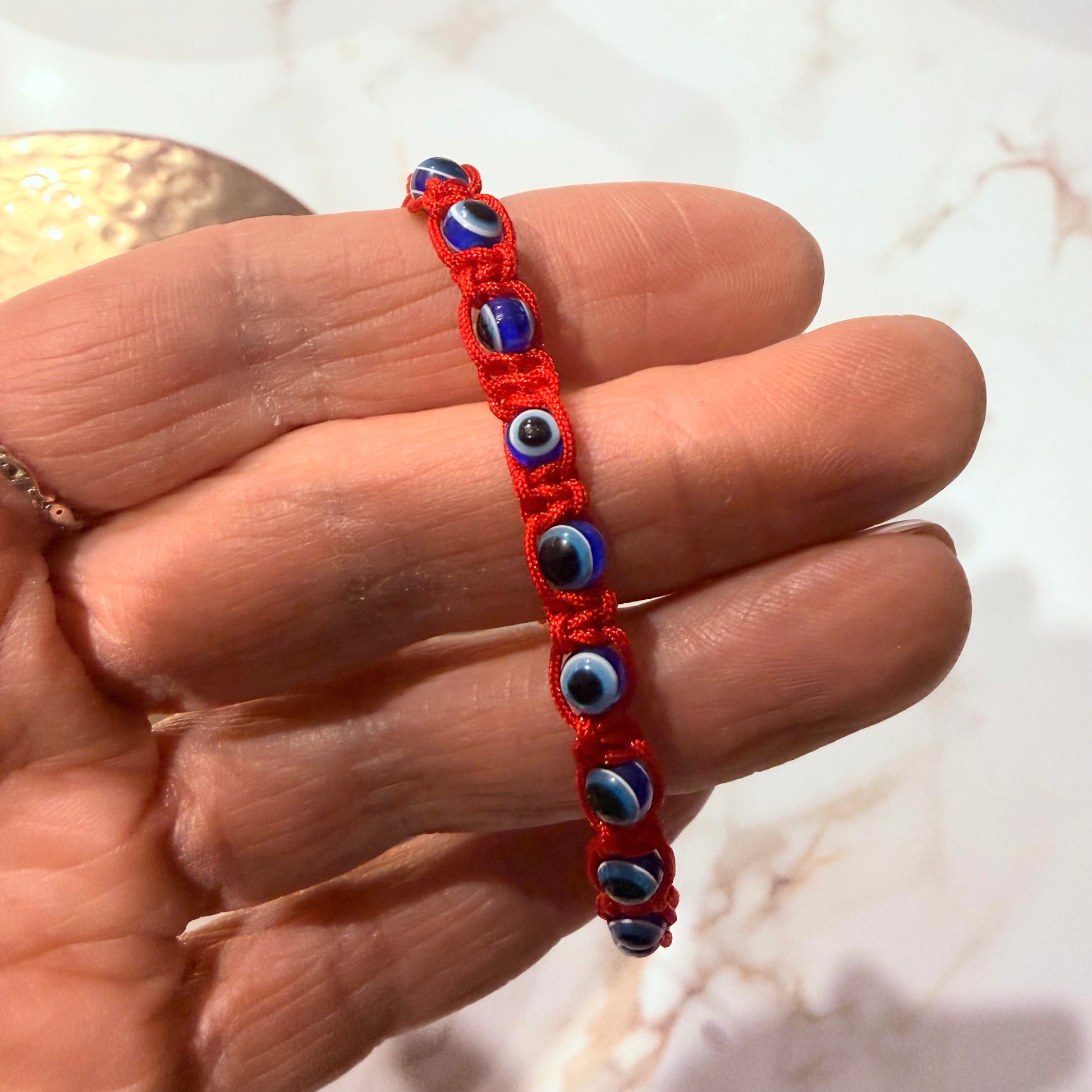Red bracelet with blue beads on a hand against a blurred background