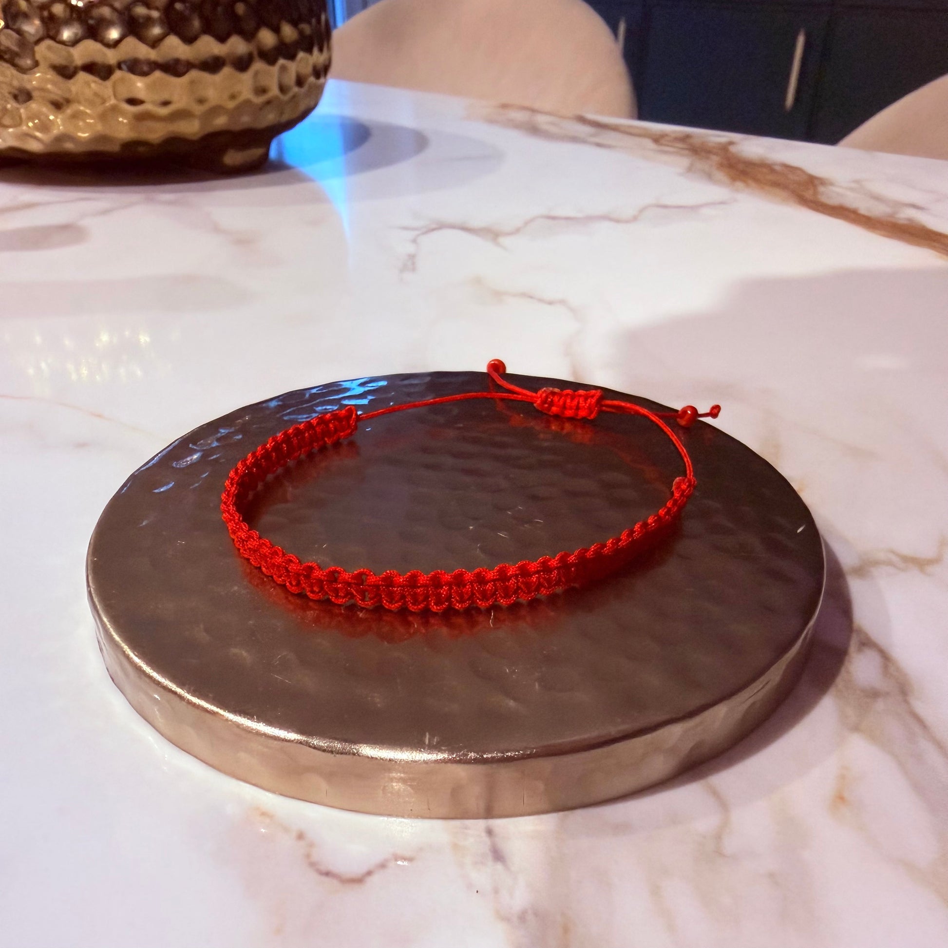Red bracelet on a metallic surface with a marble background