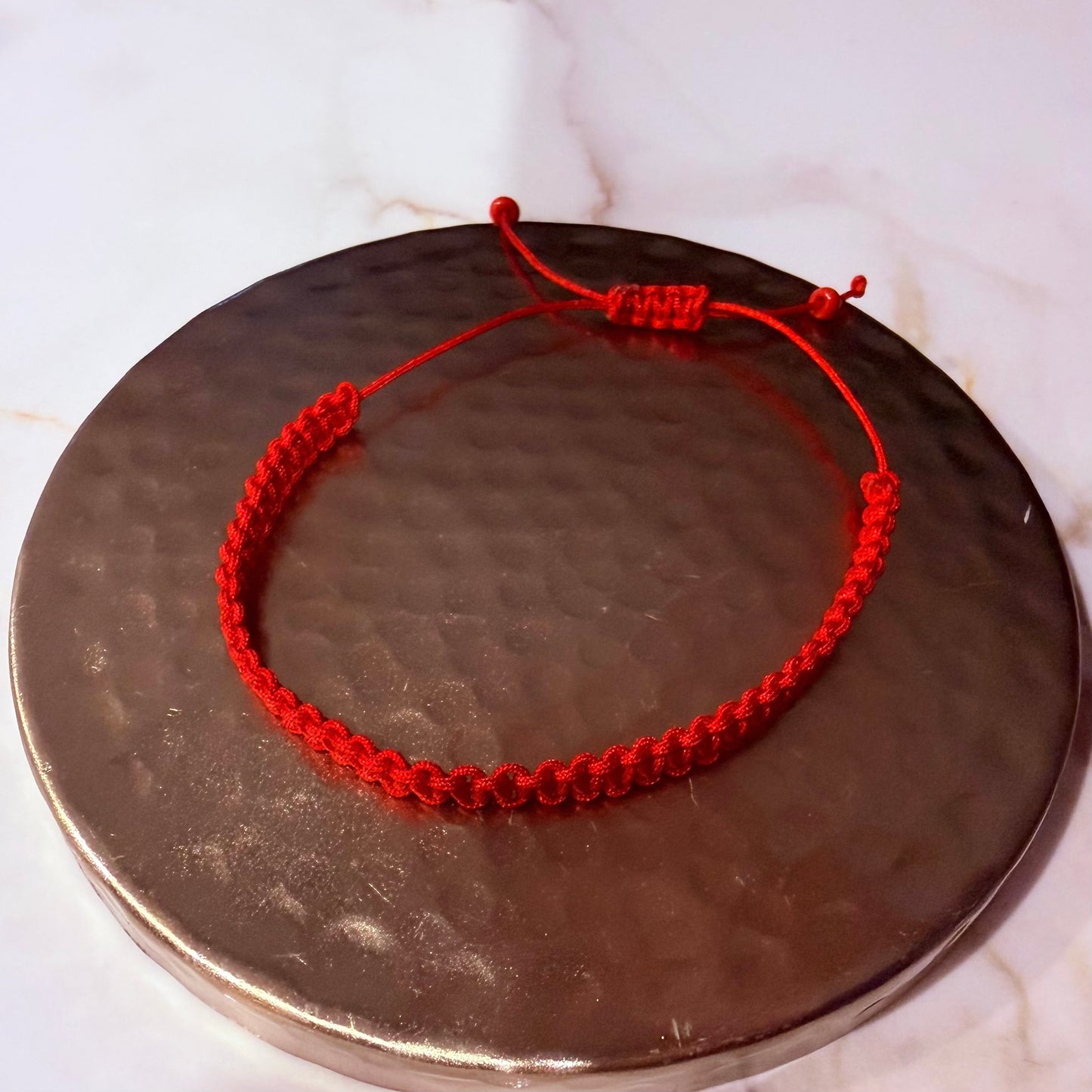 Red string bracelet on a metallic surface