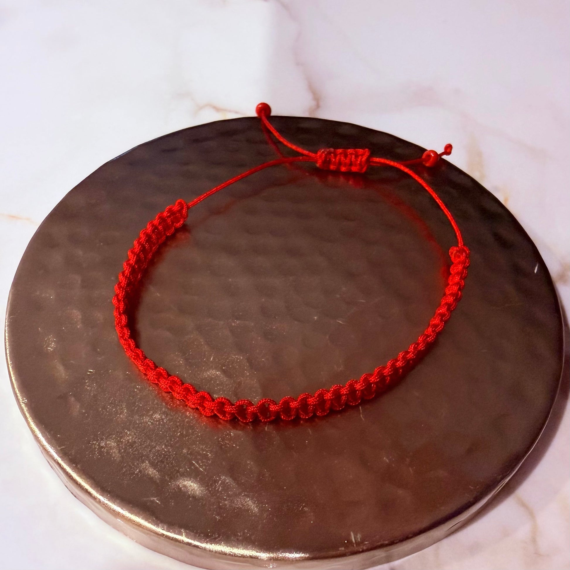 Red string bracelet on a metallic surface