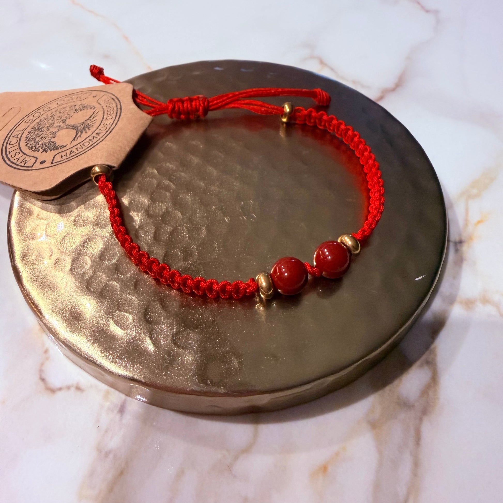 Red bracelet with gold beads on a metallic surface