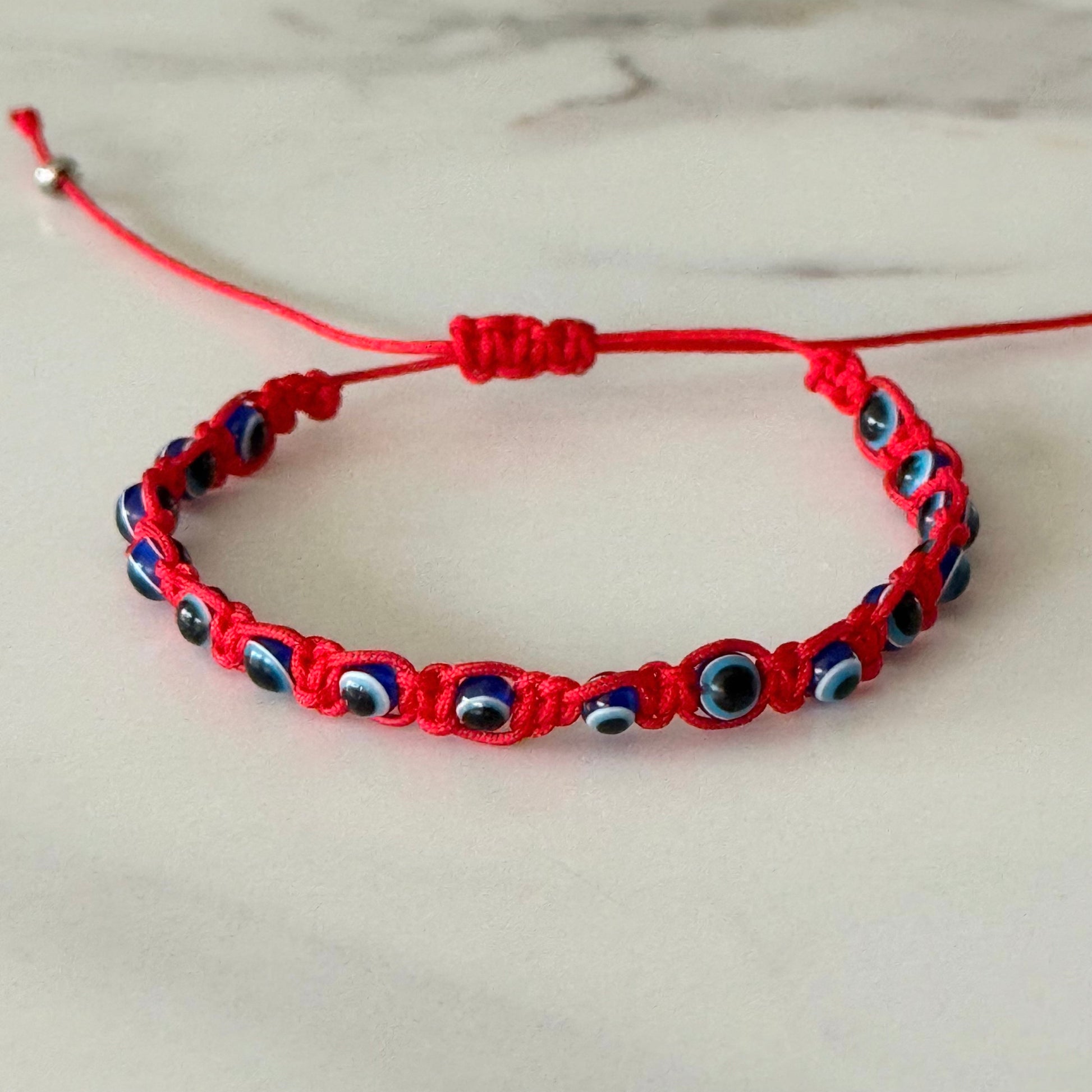 Red bracelet with blue and black beads on a light background