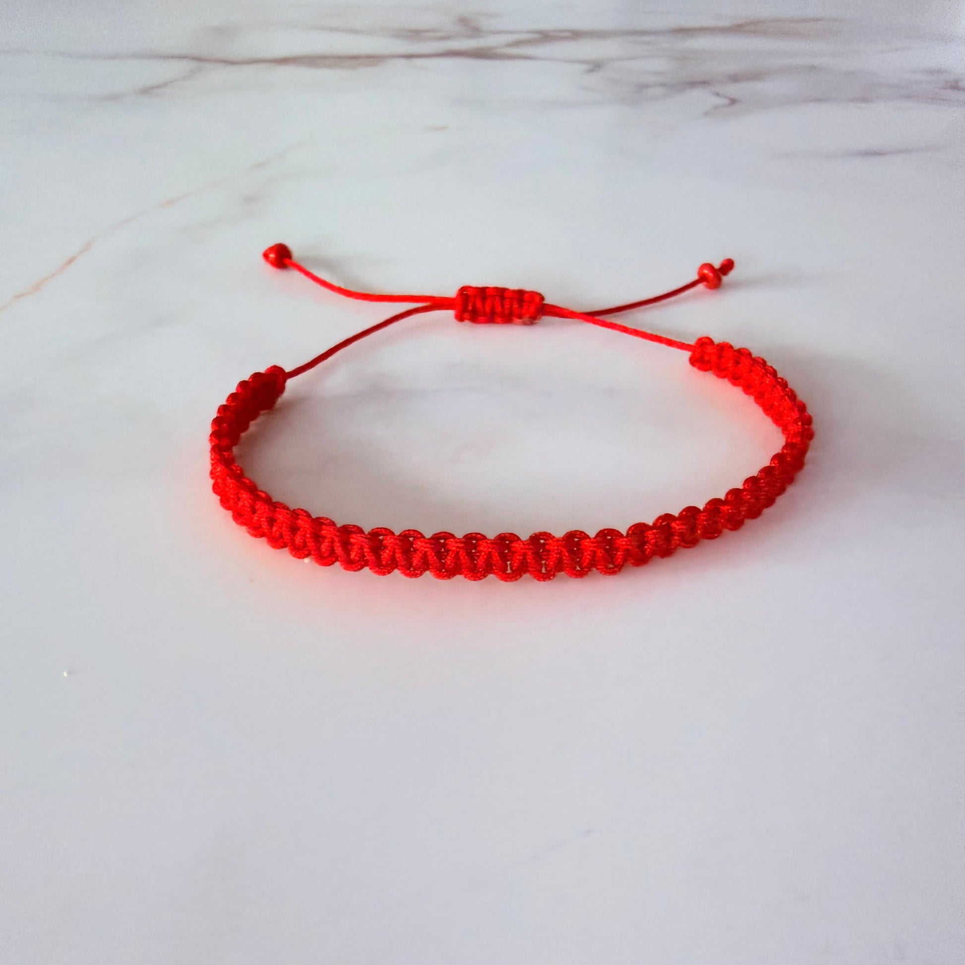 Red bracelet on a white marble surface