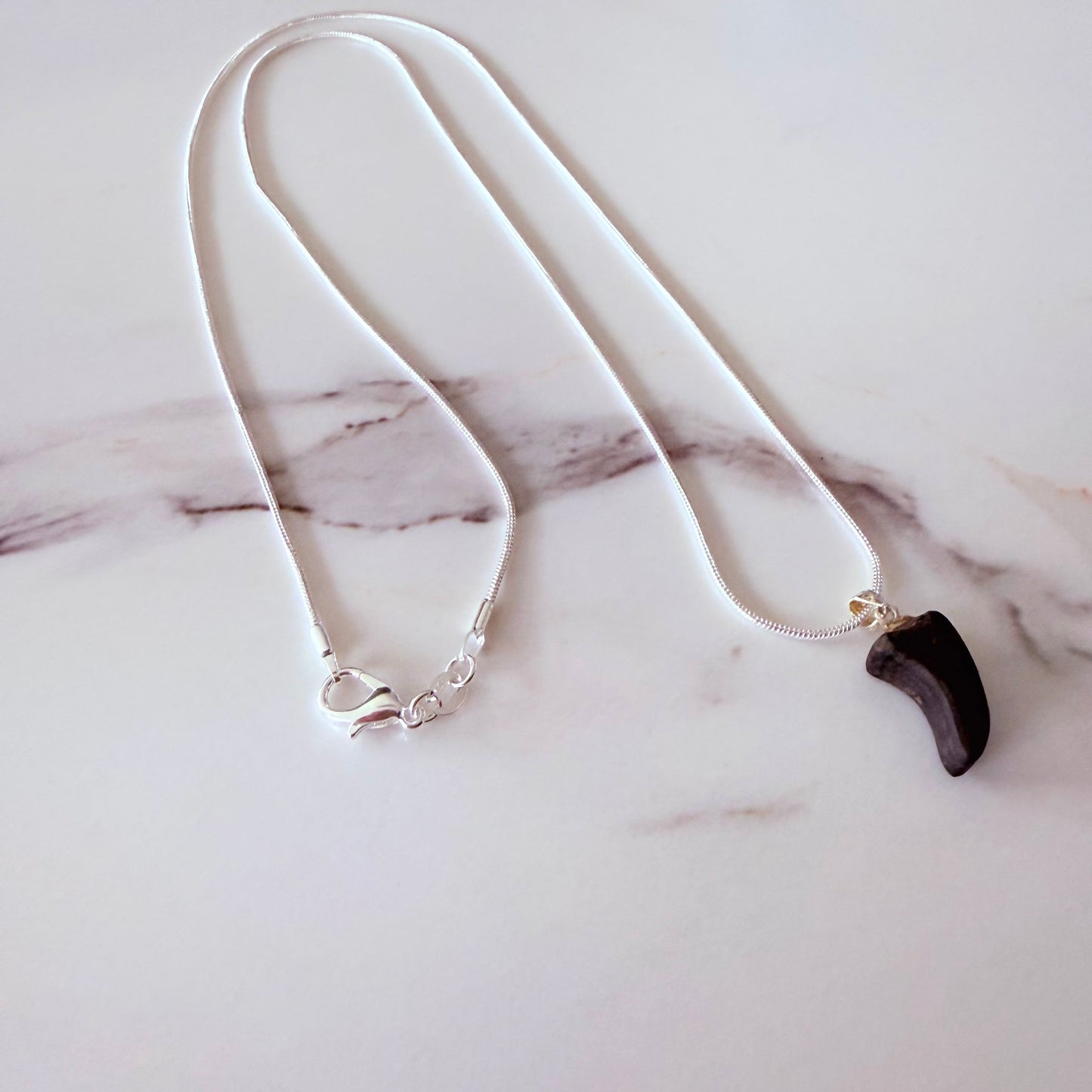 Necklace with a black pendant on a marble surface