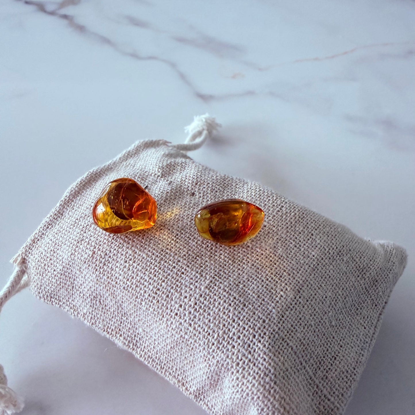 Amber-colored earrings on a textured white surface