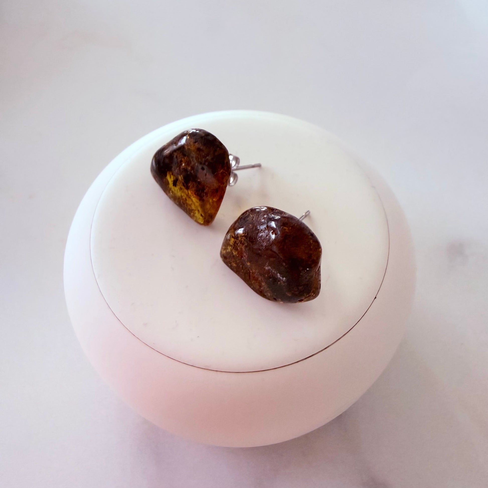 Brown stone earrings on a white round stand with a light background