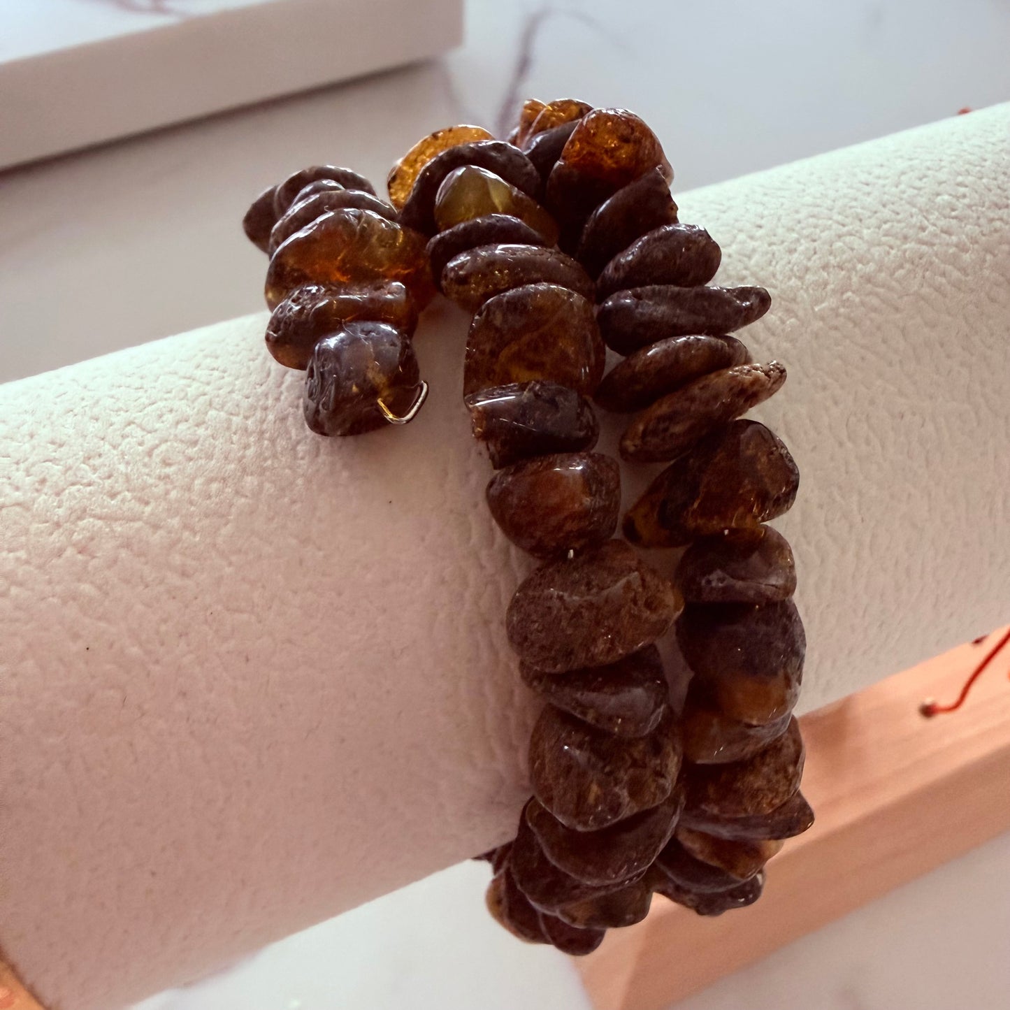 Brown beaded bracelet on a mannequin arm with a white background