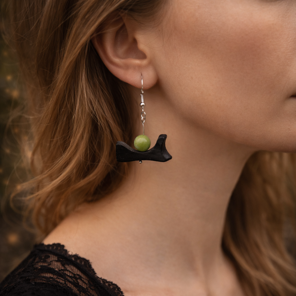 Close-up of a person wearing an earring with a green bead and black base.