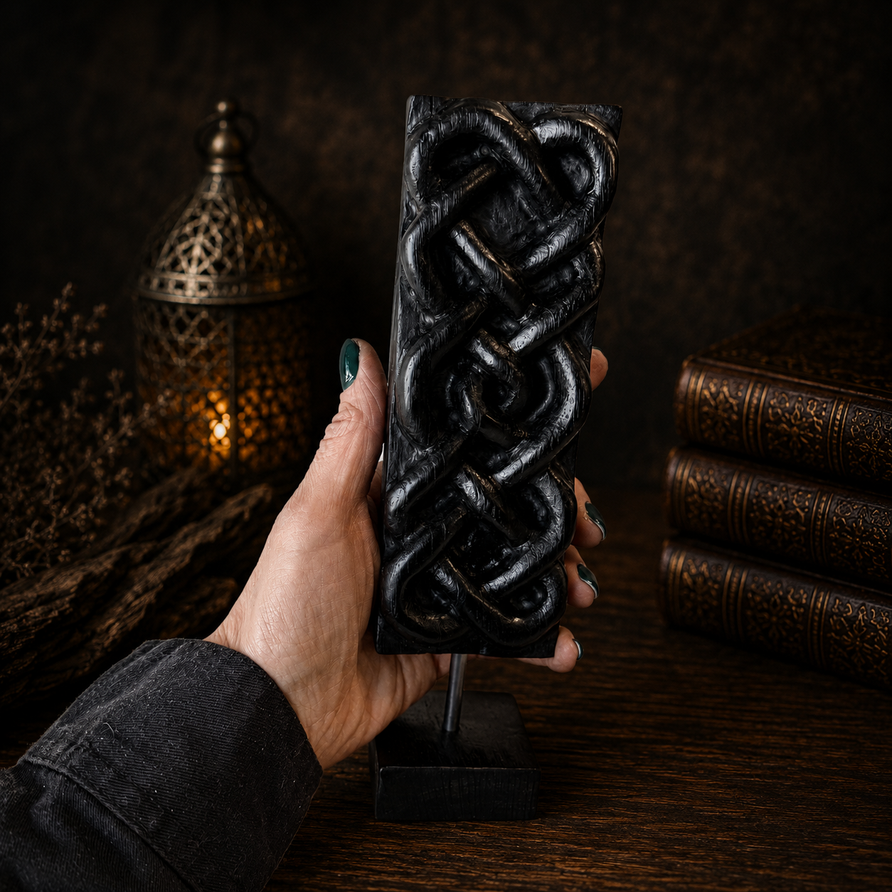 Hand holding a black decorative item with intricate patterns against a dark background