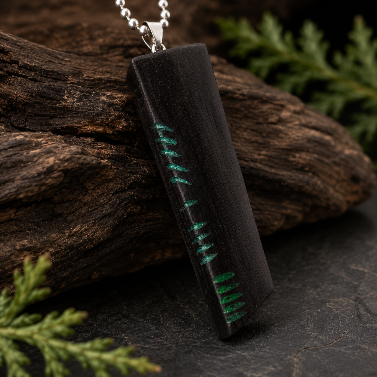 Wooden pendant with green thread on a dark surface with foliage