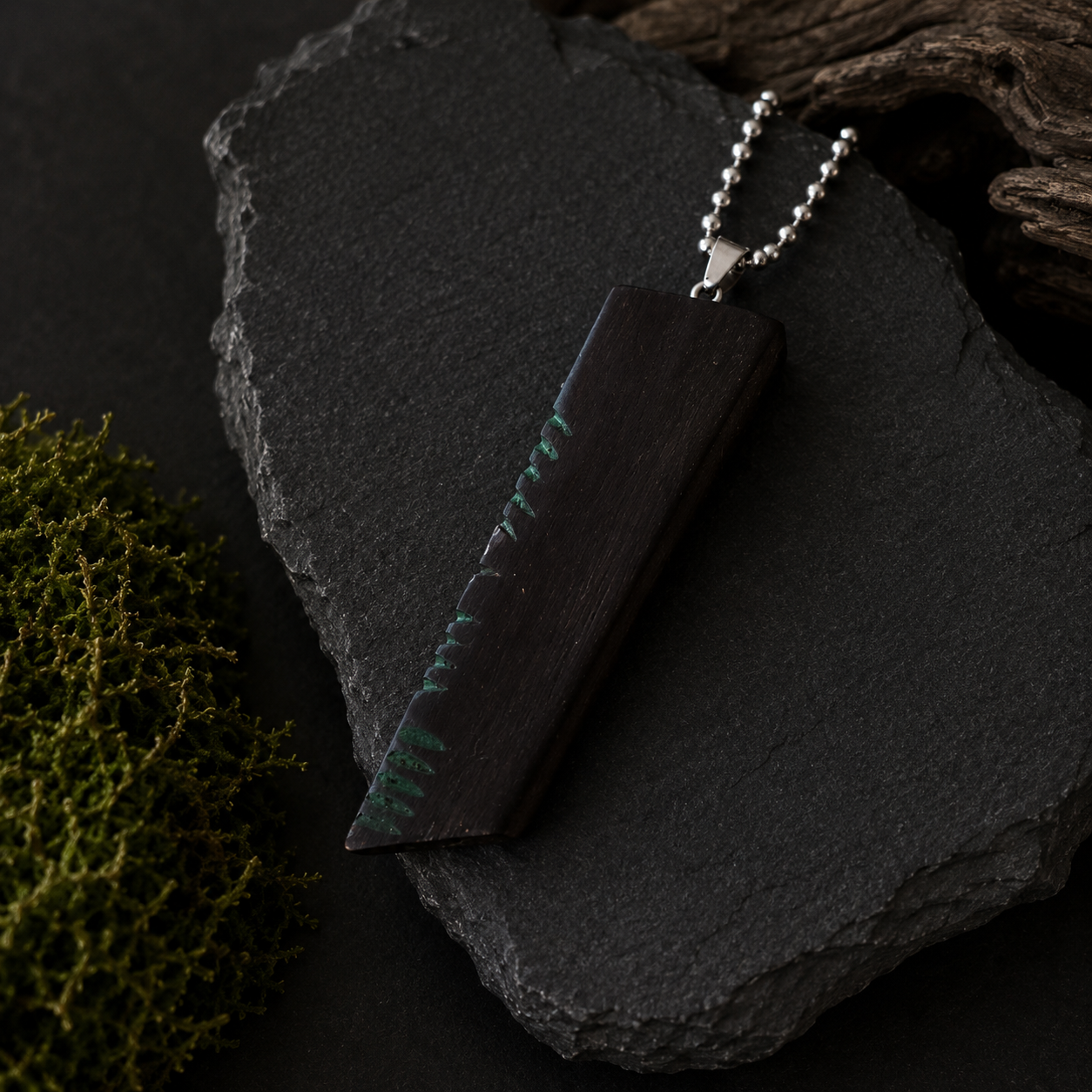 Wooden pendant with chain on a dark stone surface