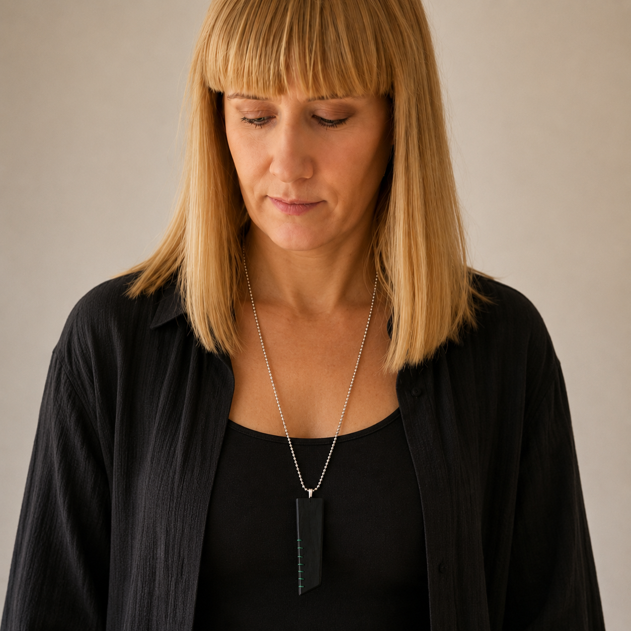 Woman wearing a black top and necklace with a neutral background