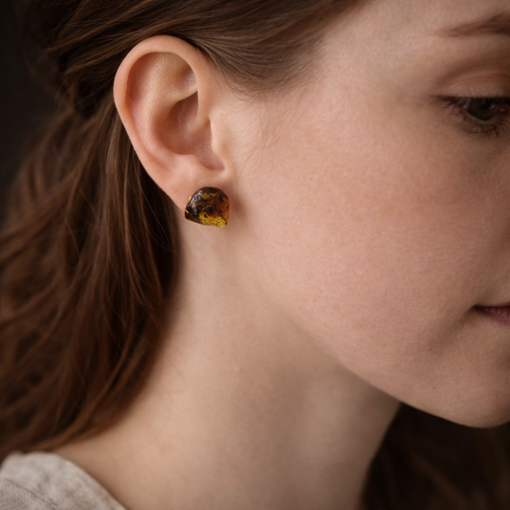 Close-up of a person wearing amber-colored stud earrings.