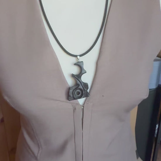 Side view of hand carved black wood pendant showing sculptural abstract form