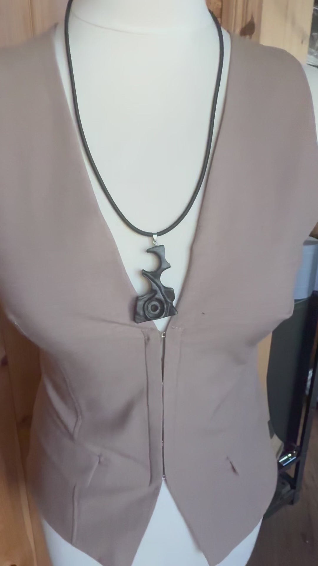 Side view of hand carved black wood pendant showing sculptural abstract form