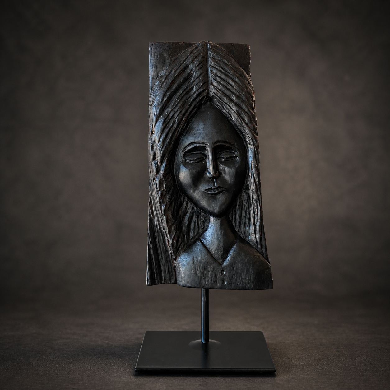 One-of-a-kind bog oak sculpture of a serene female figure with closed eyes, mounted on a black stand